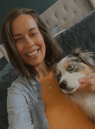Woman smiling while holding her dog close to her face
