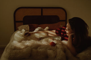 Woman lying in bed beside her dog during quiet bonding moment
