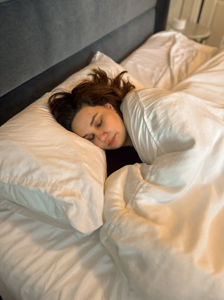 Woman resting in bed with eyes closed during recovery
