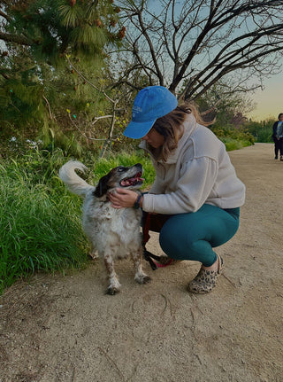 Woman crouching to pet her dog on a walking trail
