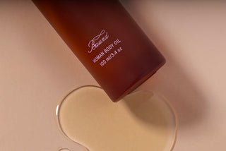 Close up of body oil bottle with oil pooled around base
